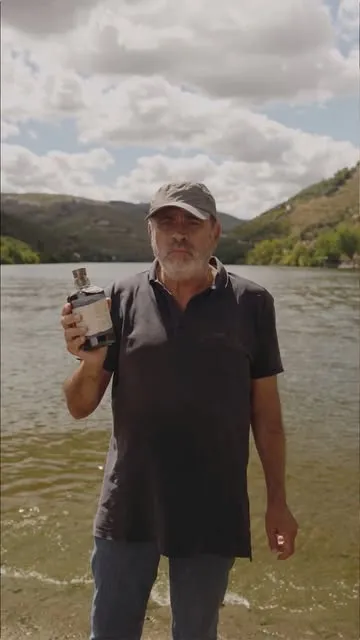 Um homem com uma garrafa junto ao rio Douro